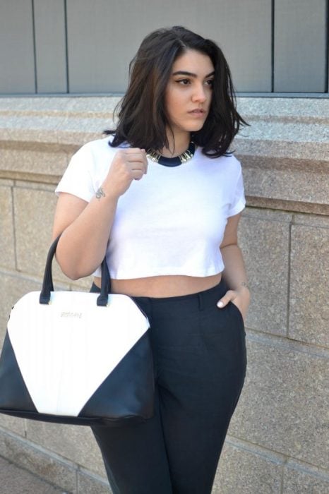 Chica curvi usando un crop top en color blanco con un pantalón en color negro 