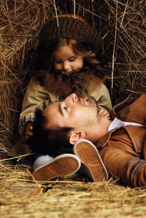 Padre e hija sentados en un establo viéndose fijamente