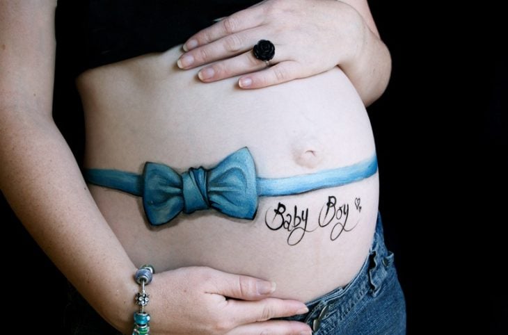 Pancita de una chica embarazada pintada con un moño