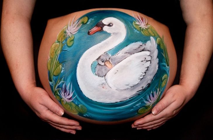 Pancita de una chica embarazada pintada con un cisne 