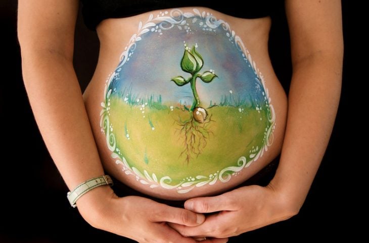 Pancita de una chica embarazada pintada con la semilla de que crece 