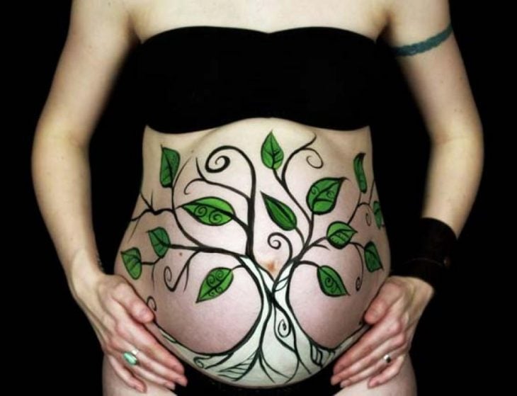 Pancita de una chica embarazada pintada con un árbol 