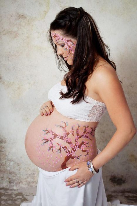 Pancita de una chica embarazada pintada con un árbol bonsai 