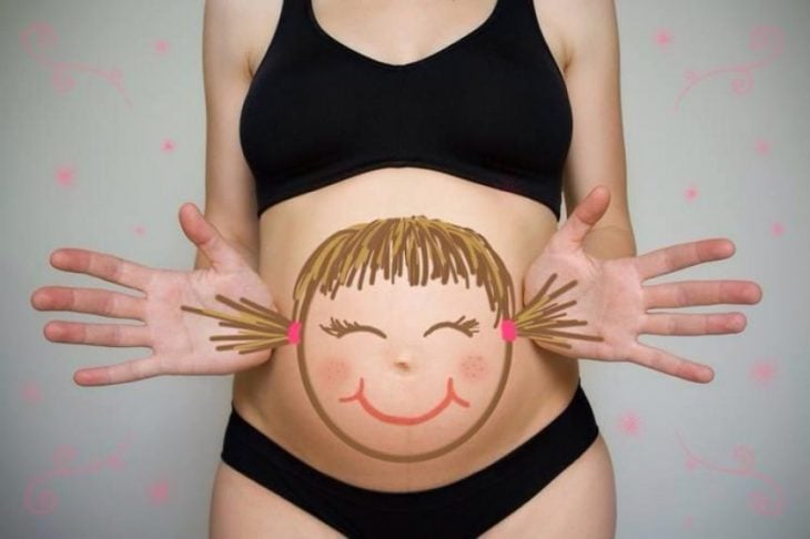 Pancita de una chica embarazada pintada con una niña con trenzas