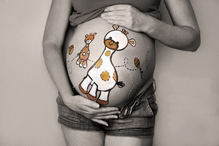 Pancita de una chica embarazada pintada con una jirafa 