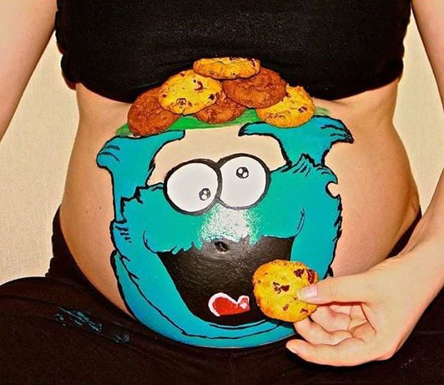 Pancita de una chica embarazada pintada con el monstruo come galletas