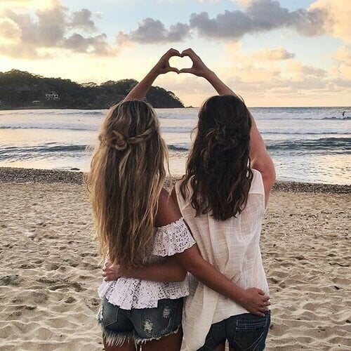 chicas en la playa haciendo señal con manos