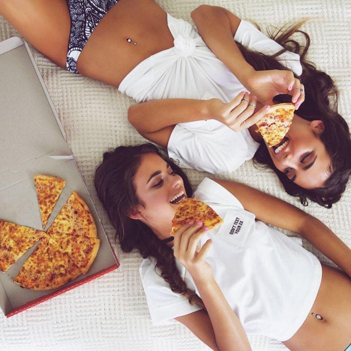 Chicas comiendo pizza recostadas en el suelo 