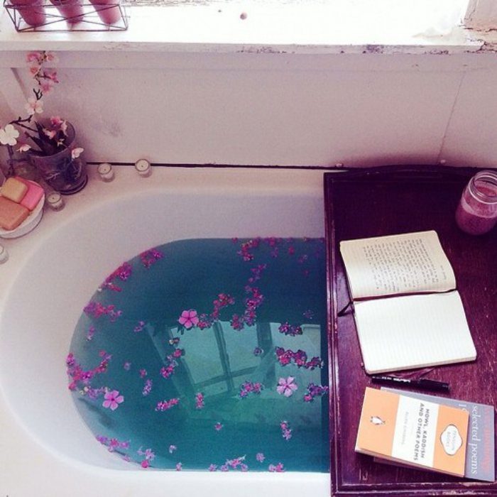 tina de baño con flores y una tabla con libros