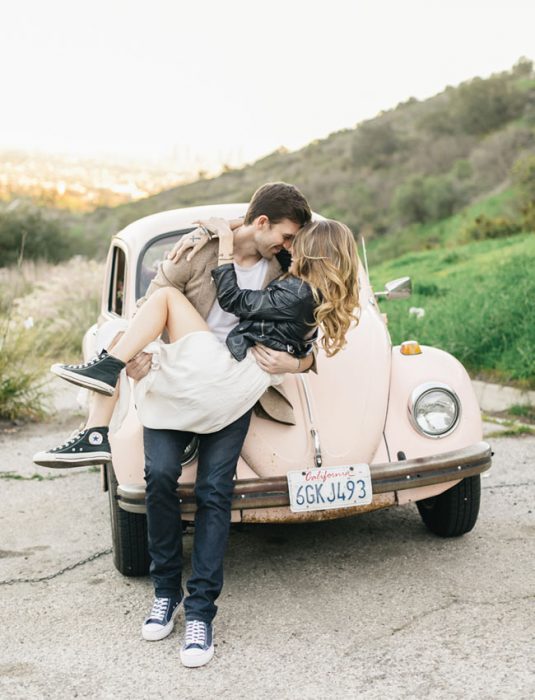 Pareja de novios besándose frente a un carro