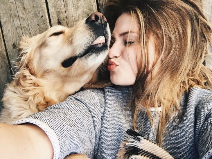 chica linda con un perro le da un beso 