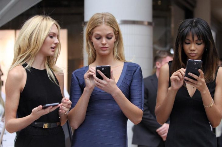 3 mujeres de frente usando su telefono