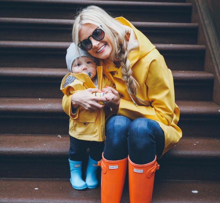 mujer rubia abrazando a su hijo con botas de lluvia