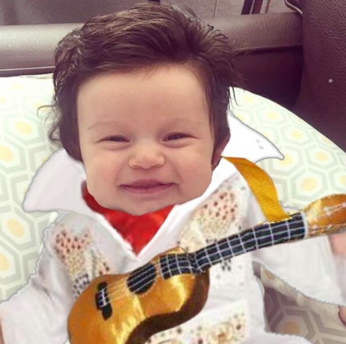 Bebé con demasiado cabello luciendo como Elvis en su traje blanco y su guitarra