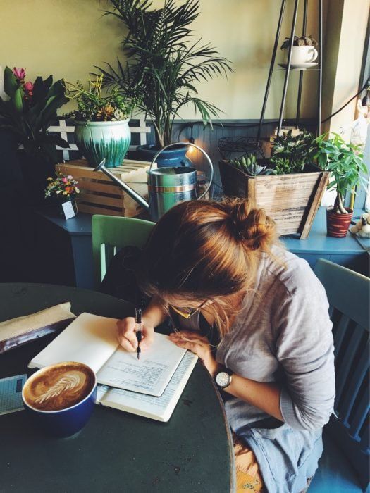 Chica escribiendo una carta en una cafetería 