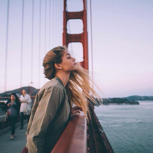 Chica recargada en un puente 