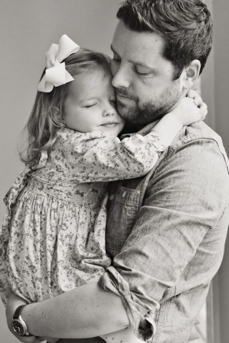 Padre sosteniendo a su hija en brazos mientras la abraza contra su pecho