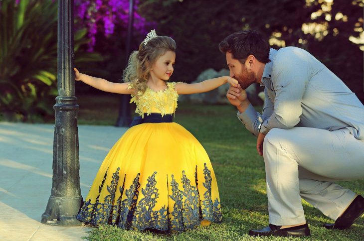 Padre besando la mano de su pequeña hija vestida de princesa 