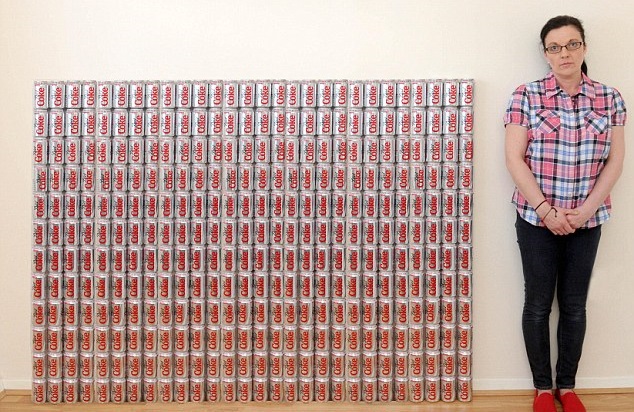 mujer con pared de latas de refresco