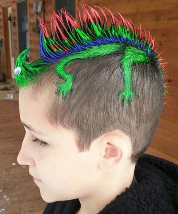 Niño con el cabello de colores simulando una iguana 