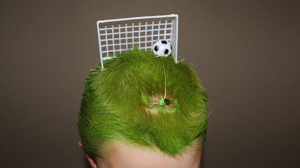 Niño con el cabello color verde simulando un campo de fútbol 