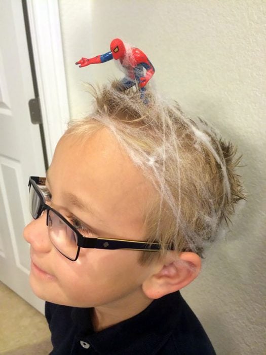 Niño con el cabello con telarañas y sobre el spiderman