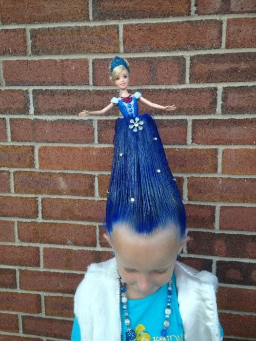 Niña con el cabello color azul con una muñeca en el 