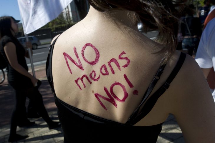Mujer con mensaje de protesta en la espalda 