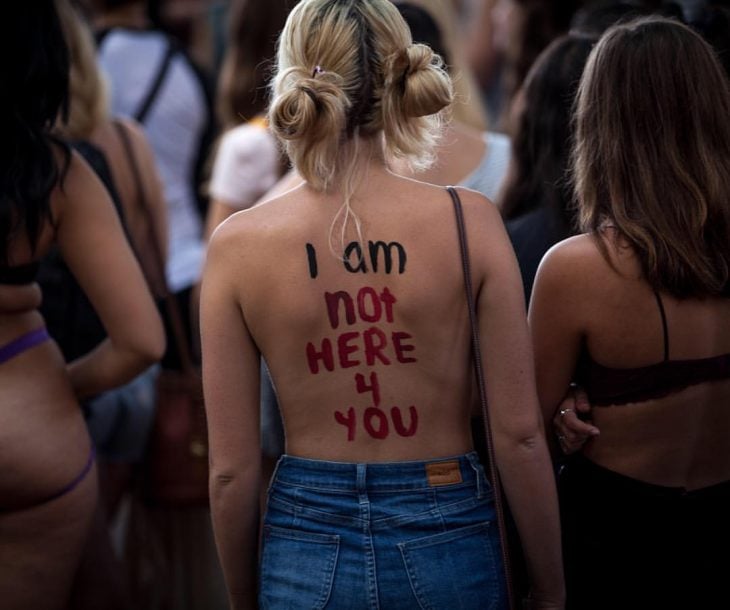 Mujer en protesta con mensaje en la espalda 