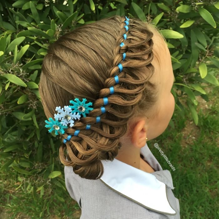 Niña con el cabello trenzado con listones azules