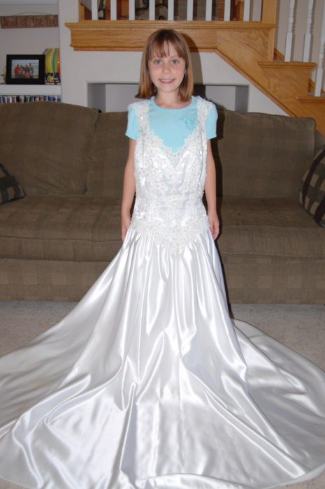 Niña usando el vestido de novia de su madre para ver su crecimiento