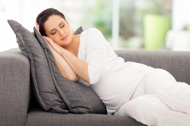 Chica embarazada durmiendo sentada en un sofá 