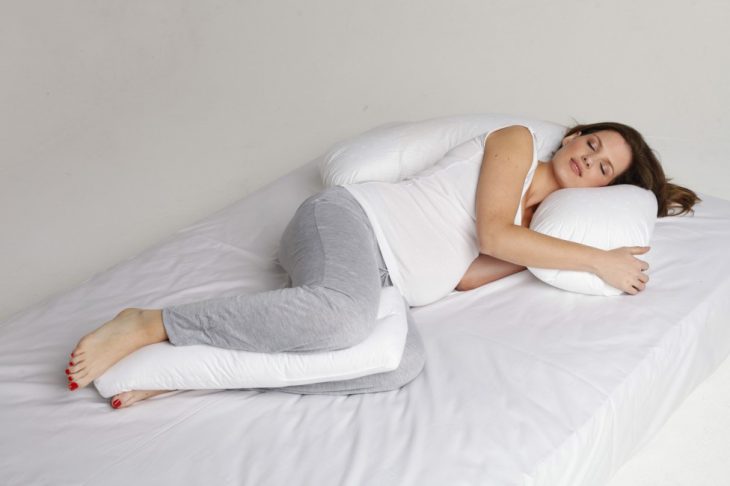 Chica embarazada durmiendo con una almohada ente sus piernas