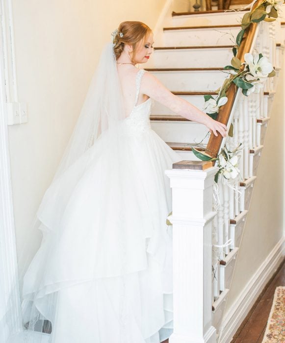 Modelo con síndrome de Down Madeline Stuart vestida de novia bajando por las escaleras 