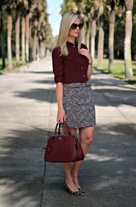 Outfits de oficina. Chica usando una falda de color gris y una blusa de color guinda 