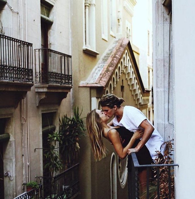 Jay Alvarrez y Alexis Ren Pareja de novios que viajan al rededor del mundo besándose en un balcón de Barcelona