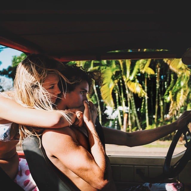 Jay Alvarrez y Alexis Ren Pareja de novios que viajan al rededor del mundo besándose mientras están conduciendo una camioneta