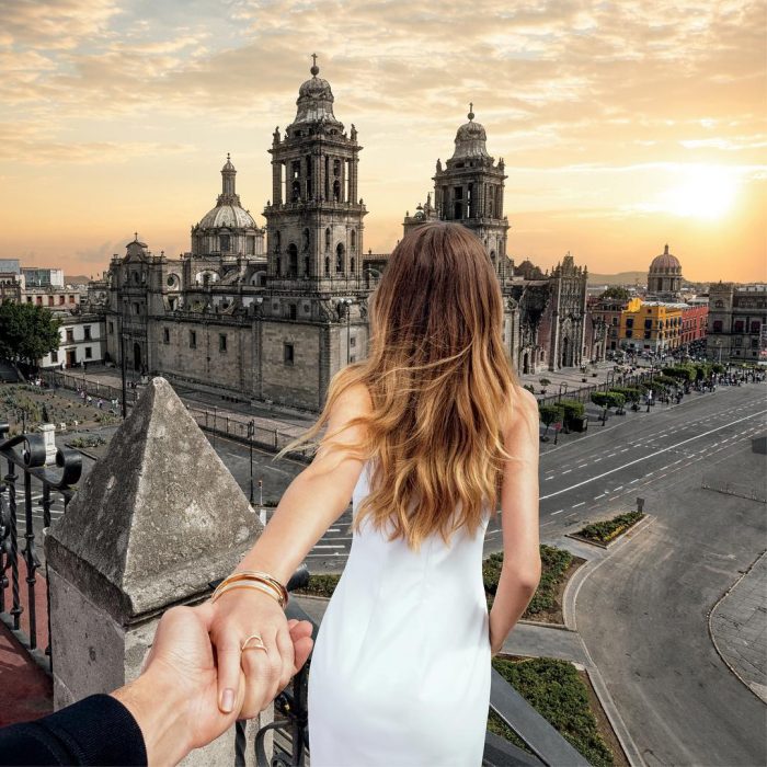 Chica dandole la espalda a un chico mientras le sujeta una mano y ven una catedral