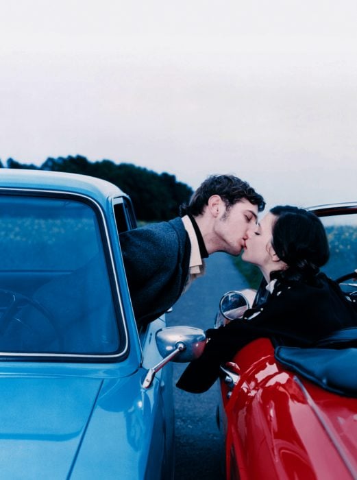 Pareja de novios en carros distintos besándose 