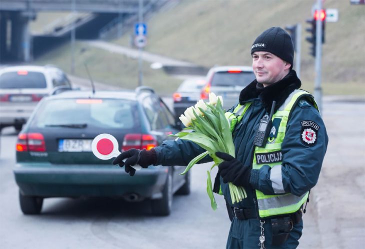 Policía sujetando un ramo de tulipanes en medio de la acera 