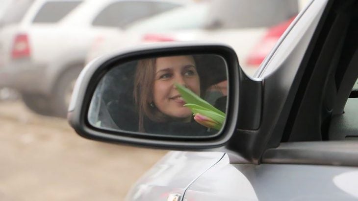 Policia entregando flores a una mujer que está conduciendo 