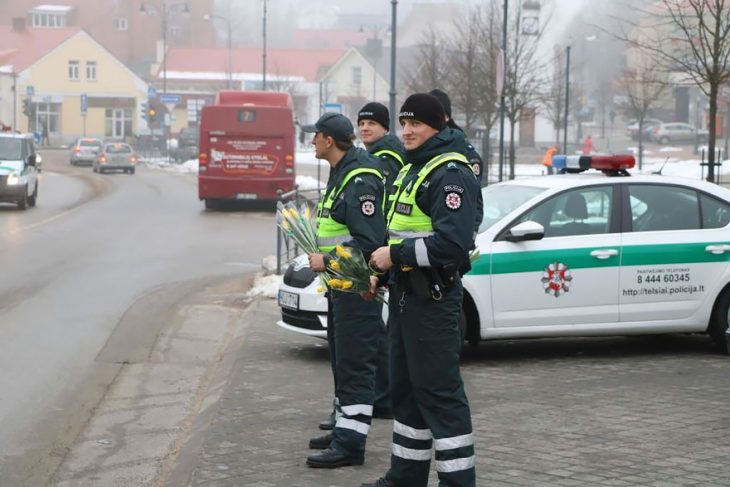 Policías sujetando ramos de tulipanes en medio de la acera 