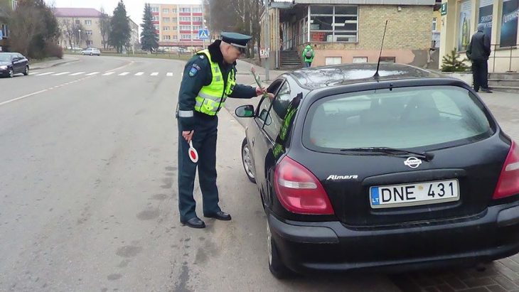 Policia entregando flores a una mujer que está conduciendo 