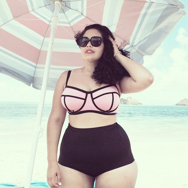 Chica Plus Size en bikini bajo una sombrilla en la playa