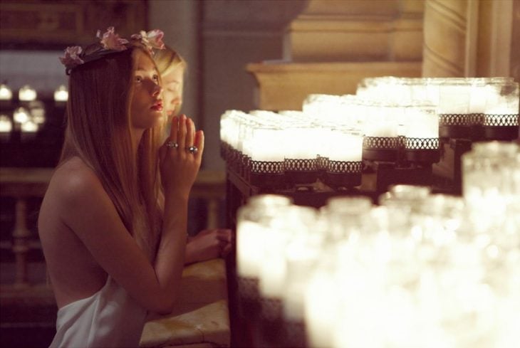 mujer rubia rezando con flores en la cabeza 