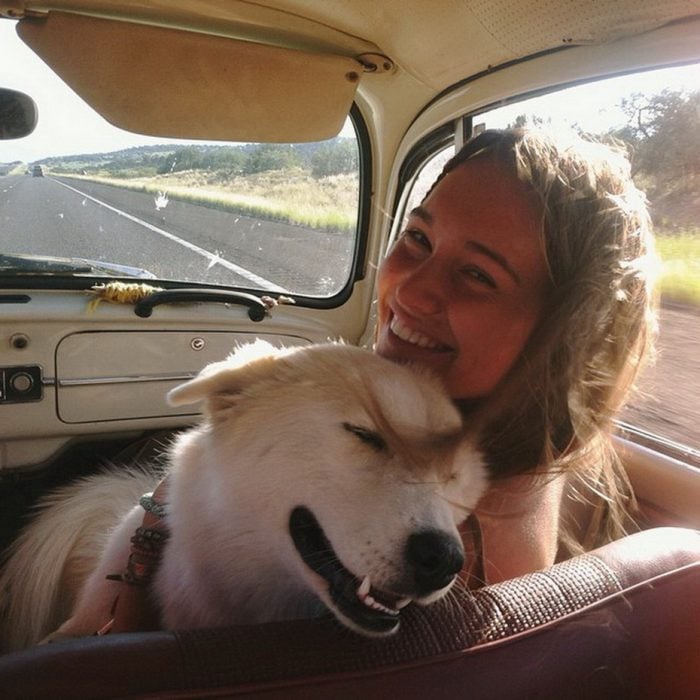 Chica y su perro de paseo en un carro 