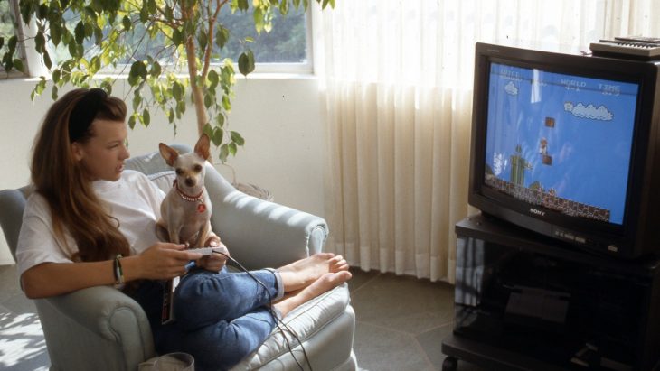 Chica jugando videojuegos junto a su perro chihuahua 