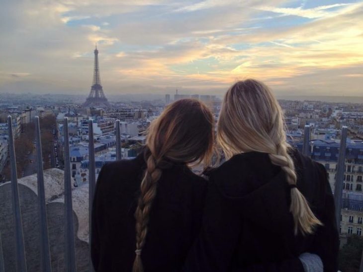 dos mujeres de espaldas con trenzas y torre eifel