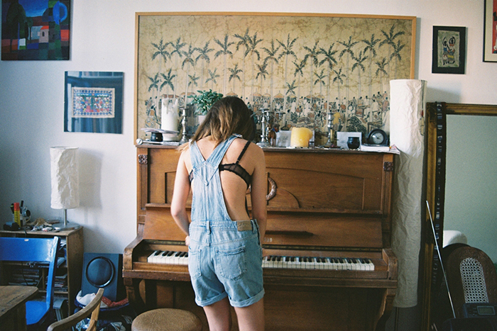 mujer con overol de espaldas tocando el piano 