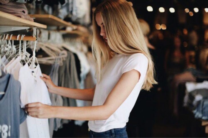 chica rubia elige ropa en una tienda